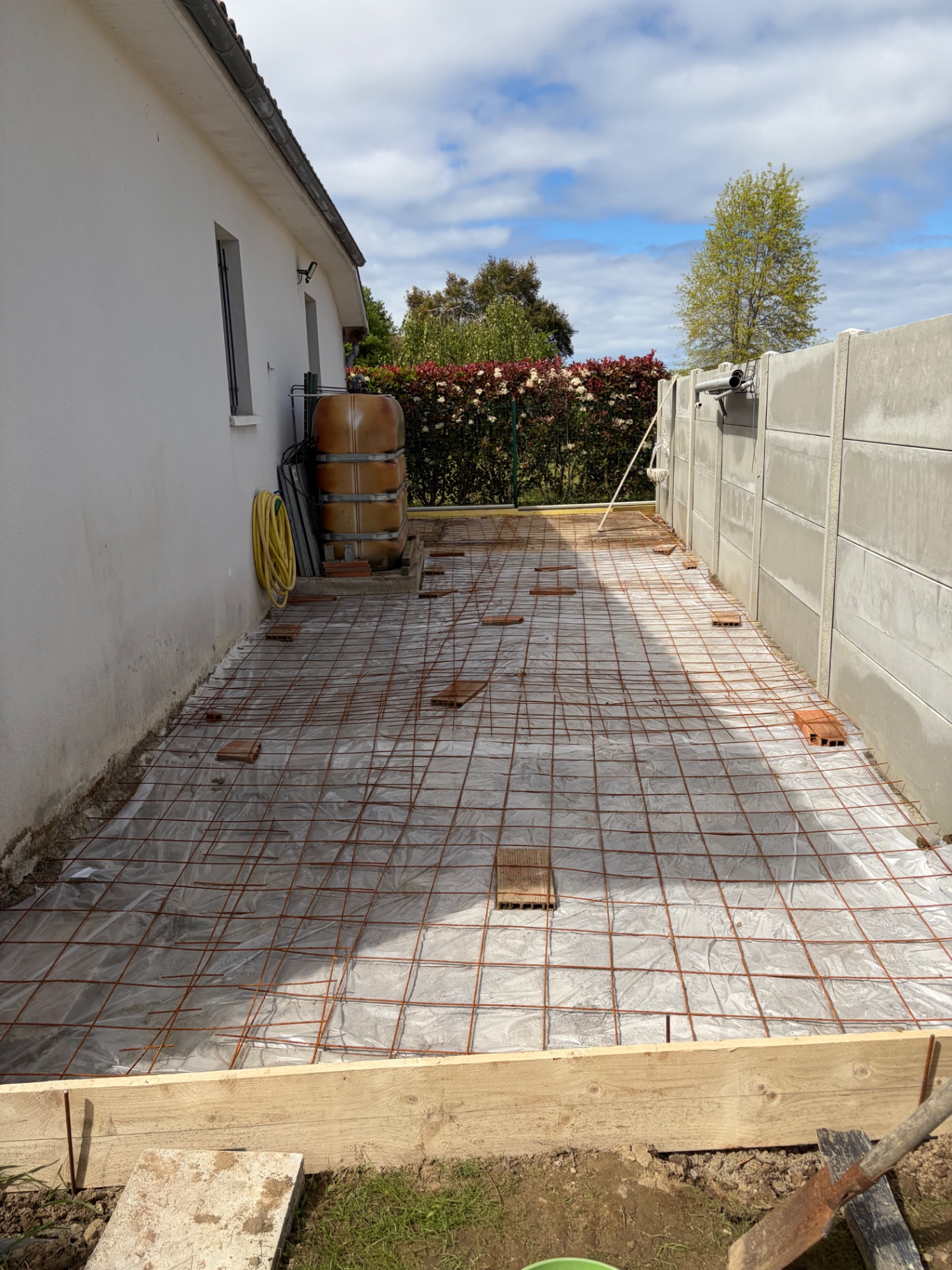 Ferraillage en treillis soudé posé sur film polyane le long de la maison, coffrage bois en rive, avant coulage de la dalle de terrasse