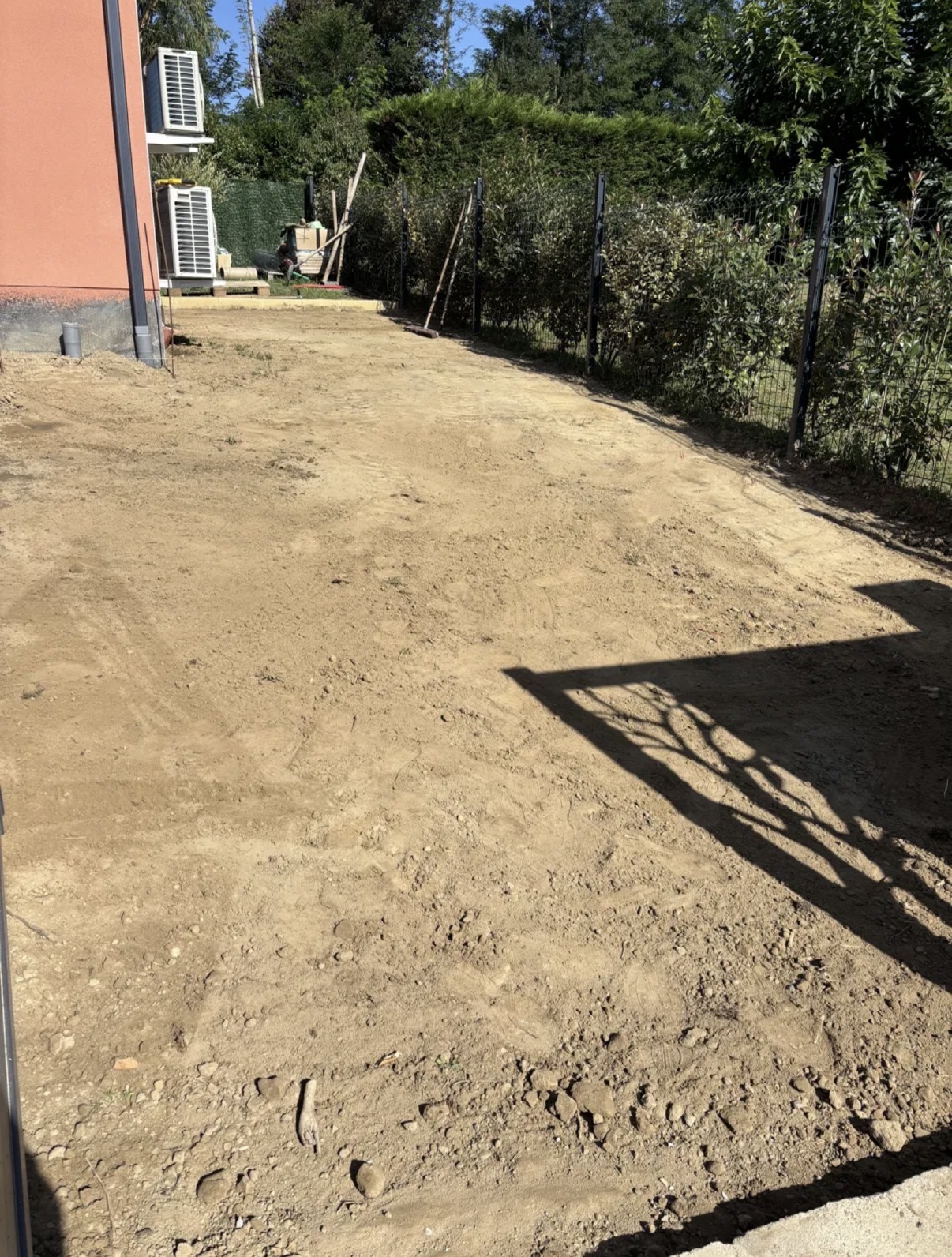 Terrain nu en terre battue avant travaux le long de la maison, descentes d'eau et regards apparents